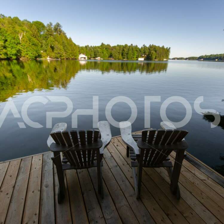 Adirondack chairs facing a calm lake 2904