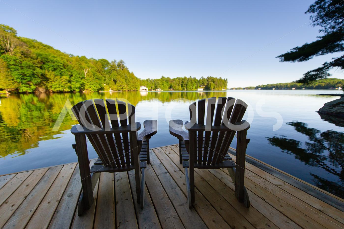 Adirondack chairs sitting on a wooden dock 2892