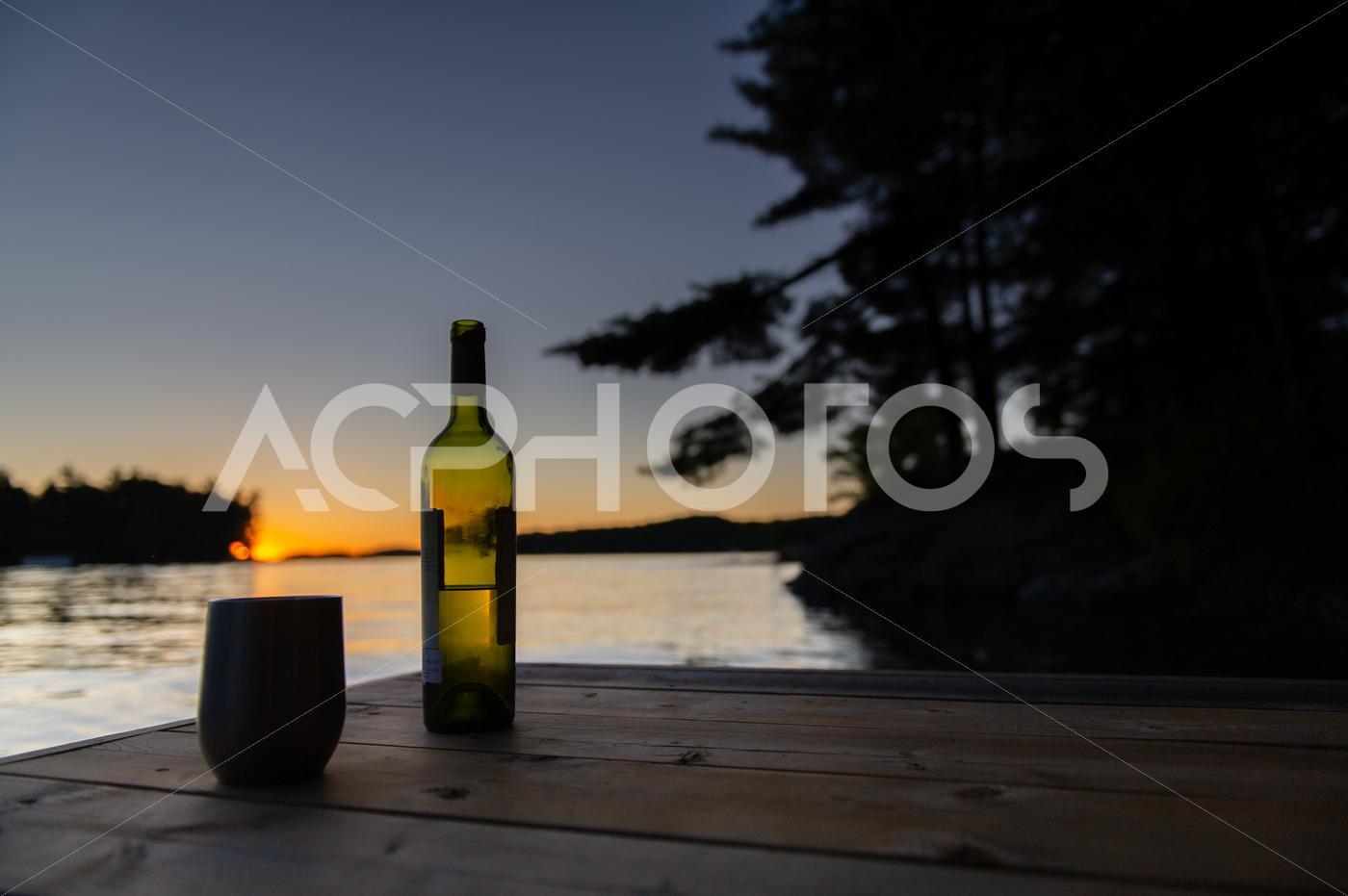 Bottle of wine and a tumbler glass at sunset 2874