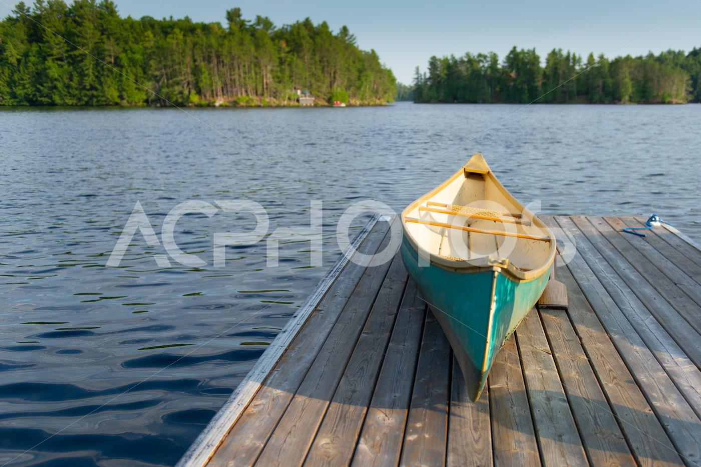Green canoe sitting on a lake wooden pier 2492