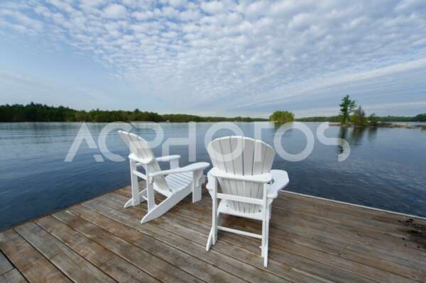 Two white Adirondack chairs on a lake in Ontario - GettaPix
