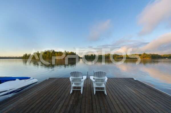 White Adirondack chairs on a lake at sunrising - GettaPix