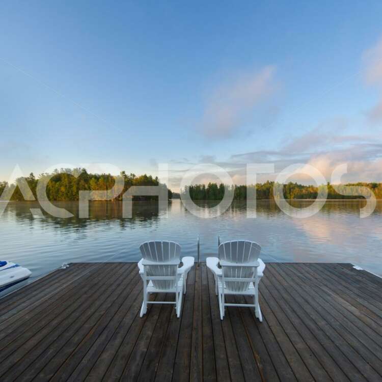 White Adirondack chairs on a lake at sunrising 3496