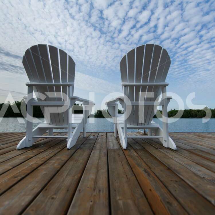 White Muskoka chairs on a wooden dock - GettaPix
