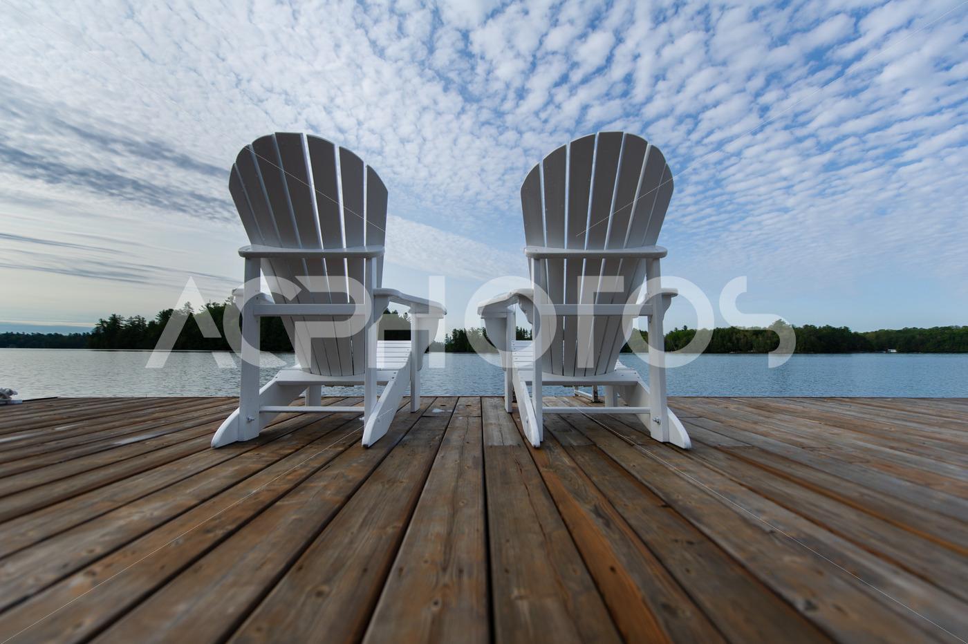 White Muskoka chairs on a wooden dock 3524