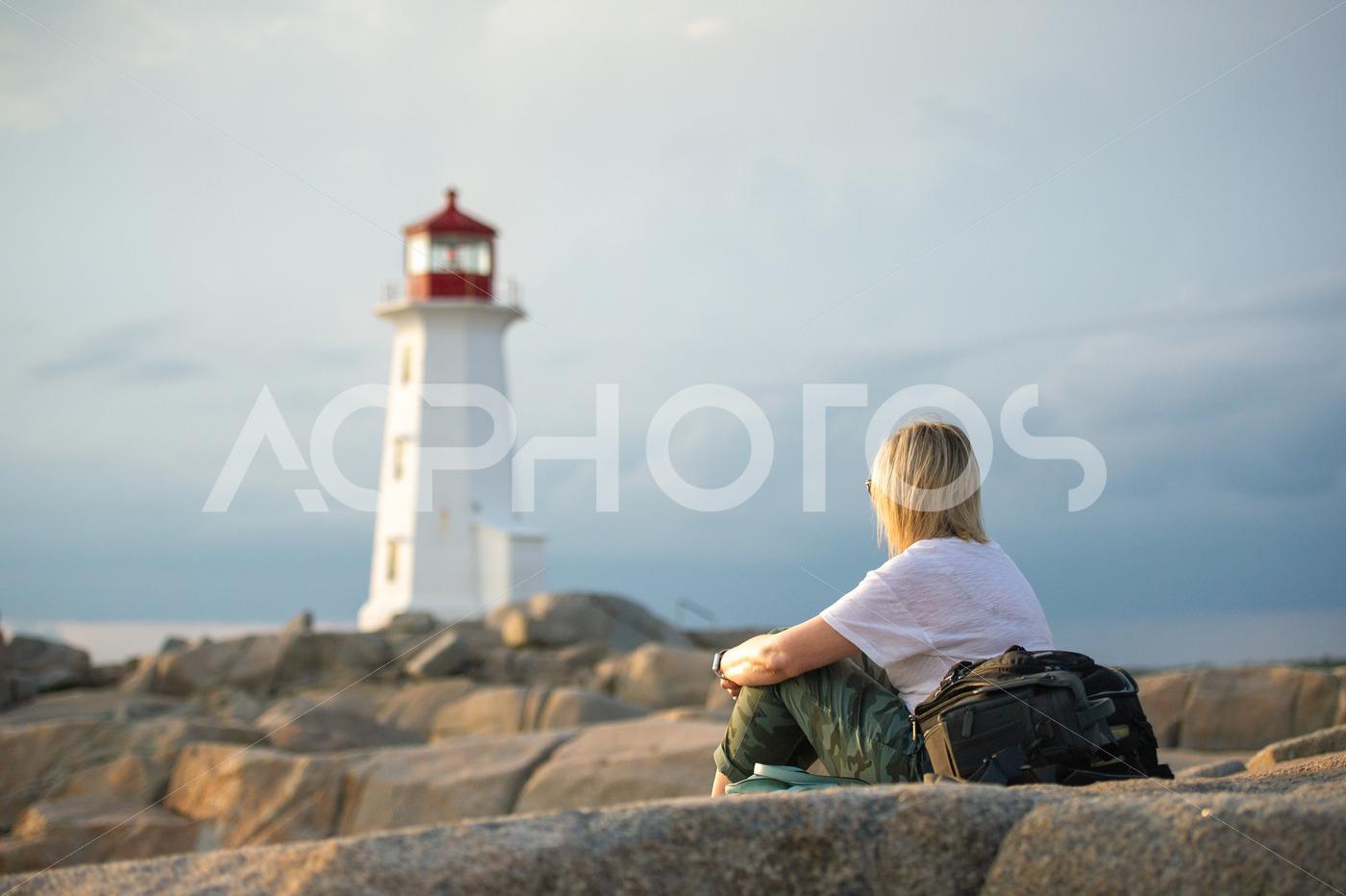 Young woman sitting on Peggy’s Cove rock - GettaPix