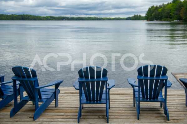 Blue Adirondack chairs on a wooden dock - GettaPix
