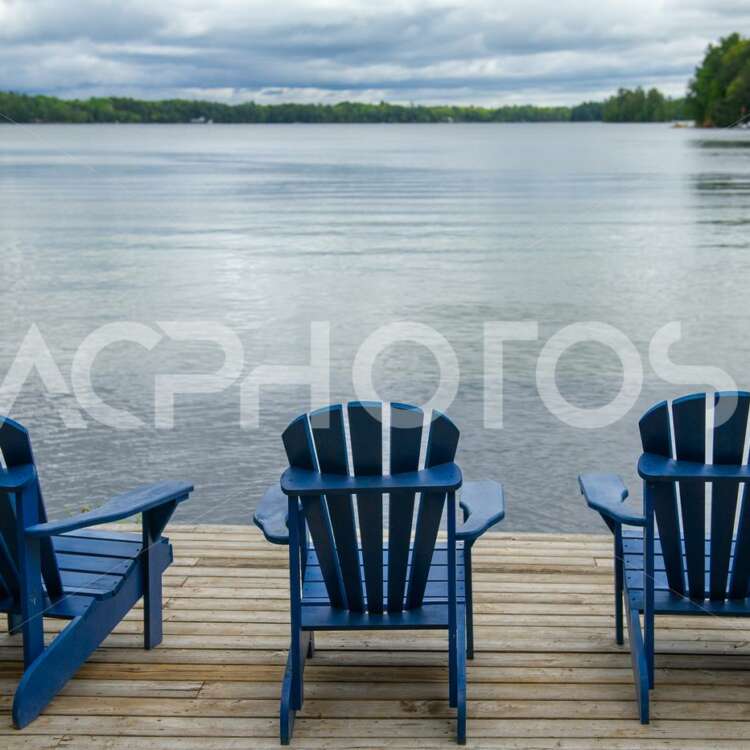 Blue Adirondack chairs on a wooden dock - GettaPix