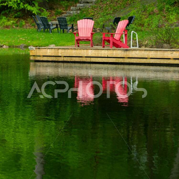 Two Adirondack chairs on a wooden dock - GettaPix
