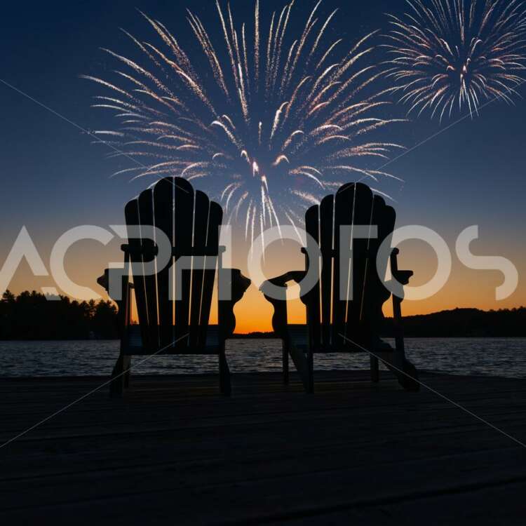 Two empty Adirondack chairs during fireworks on the lake - GettaPix