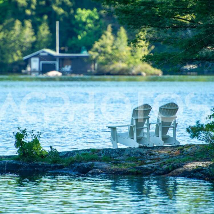 Two white Adirondack chairs on a rock formation - GettaPix