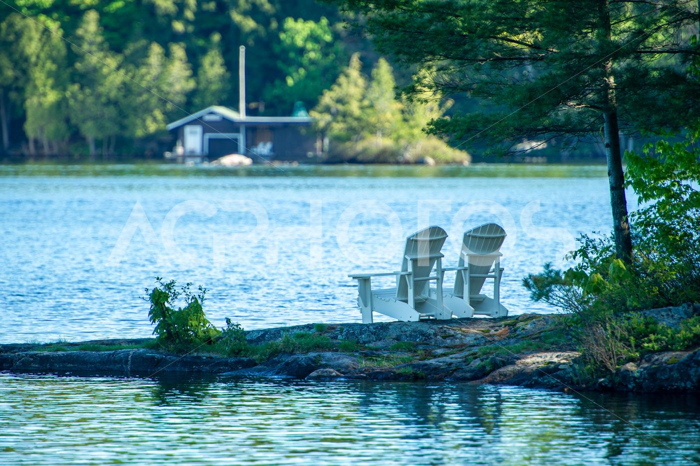 Two white Adirondack chairs on a rock formation - GettaPix