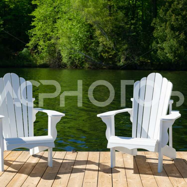 Two white Adirondack chairs on a wooden dock - GettaPix