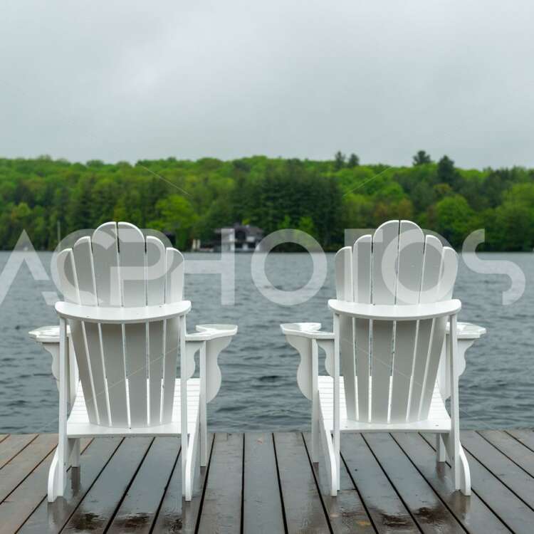 Two white Adirondack chairs on a wookend dock - GettaPix