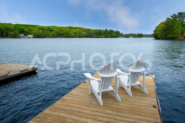 Two white Adirondack chairs on a wookend dock - GettaPix