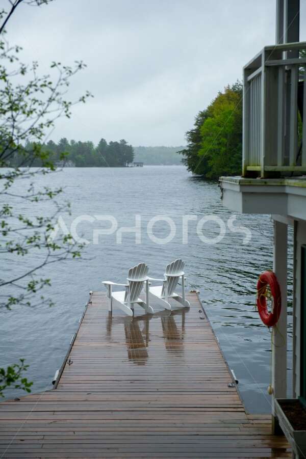 Two white Adirondack chairs on a wookend dock in Muskoka - GettaPix
