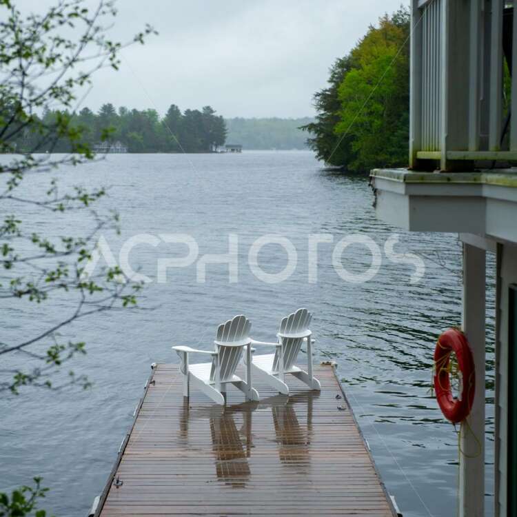 Two white Adirondack chairs on a wookend dock in Muskoka - GettaPix