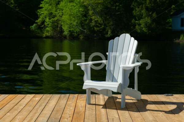 White Adirondack chair sitting on a wooden dock - GettaPix